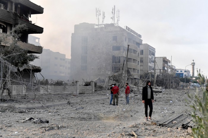 People standing on a street near damaged buildings following an Israeli air strike in the  Dahieh district in Beirut, Lebanon on October 6 2024