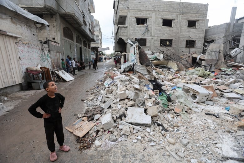 A Palestinian kid looks on at the site of an Israeli strike on a house.