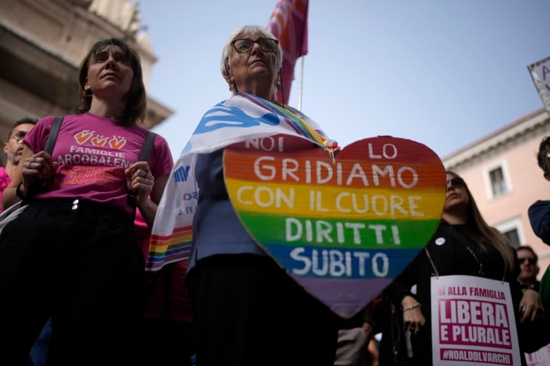 Protestors hold rainbow-coloured signs with slogans written in Italian