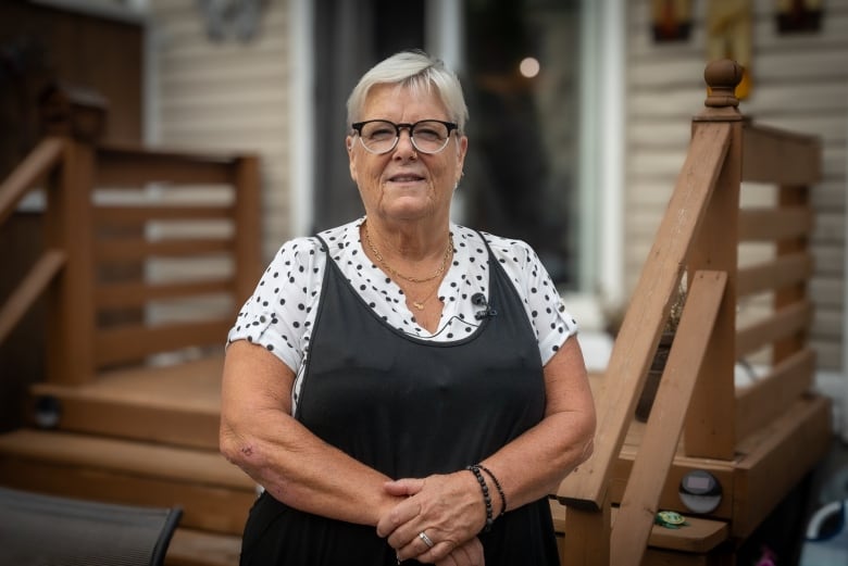 a woman standing outside on her deck with her arms crossed. 