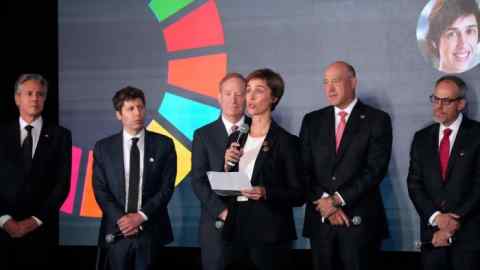 Joelle Pineau speaks into a microphone as others stand on stage