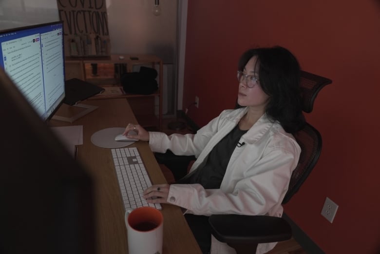 Image of Toronto lawyer Danika So at her desk, reviewing documents on her computer screen.