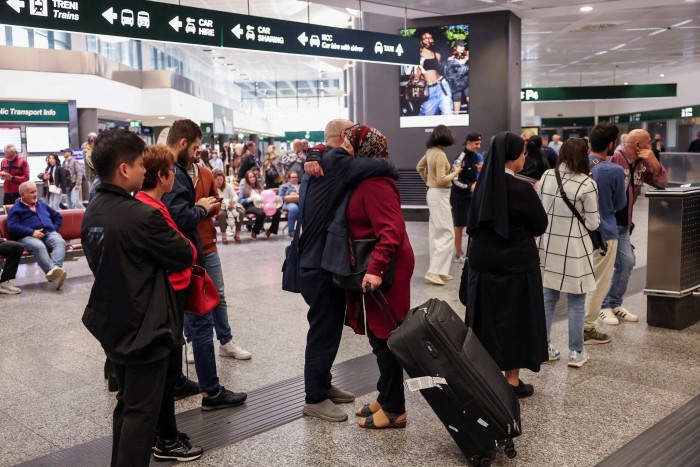 A passenger arriving from Beirut hugs a person inside the arrival terminal of Malpensa airport in Milan, Italy