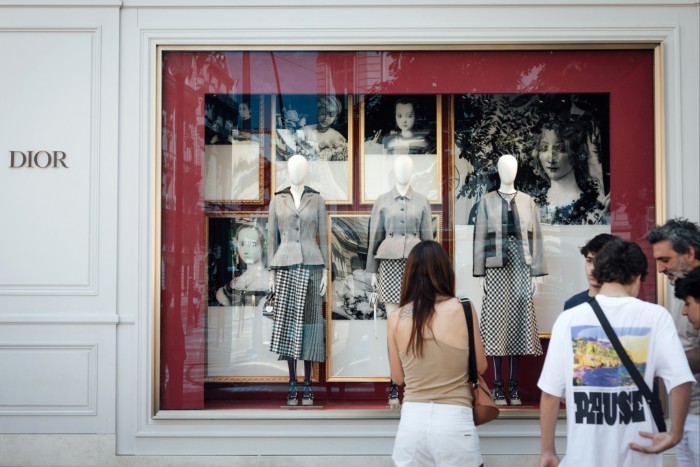 A shopper browses the window display of a Christian Dior SE store in Paris