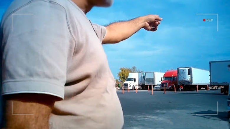 A man points at trucks parked in a parking lot.