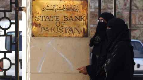 Women walk past the State Bank of Pakistan in Karachi