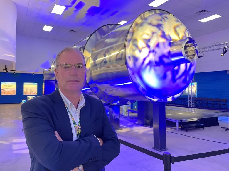 Man stands next to a cylinder model of a nuclear reactor. 