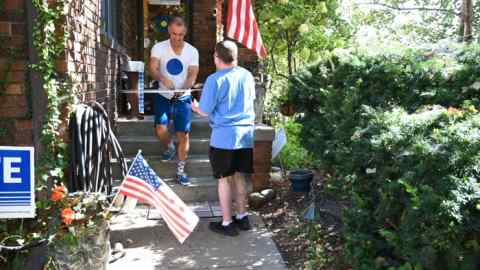 Jason Brown gives a neighbour a handcrafted political sign at his home in Omaha, Nebraska