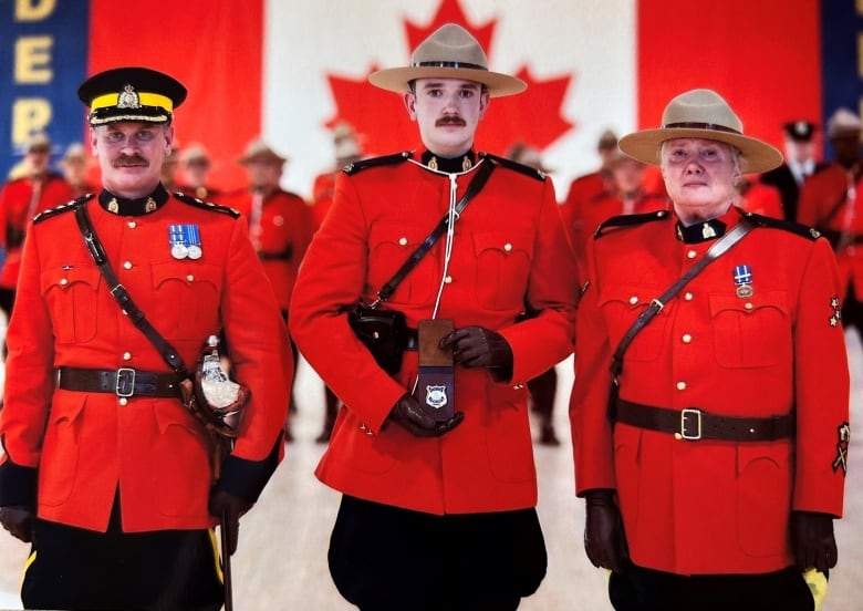 Three RCMP officers pose. The one in the centre is carrying a badge.