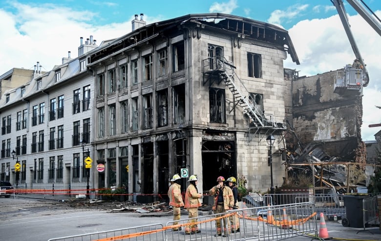 Firefighters stand next to a building in Old Montreal on Saturday, Oct., 5, 2024. 