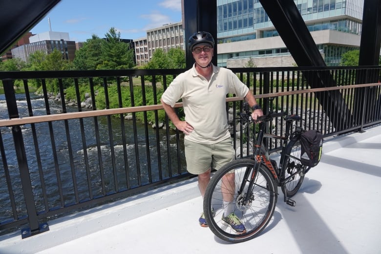 Kitchissippi Ward Coun. Jeff Leiper stands on a multi-use bridge with his bicycle.