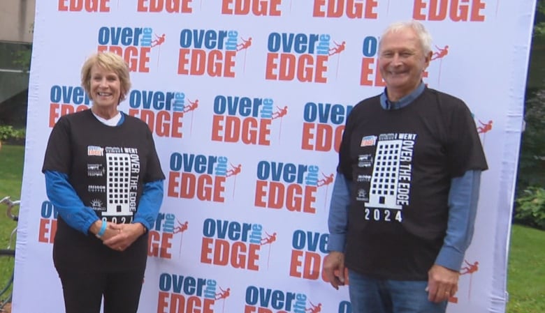 A photo of two people posing in front of a background that says "Over the Edge"