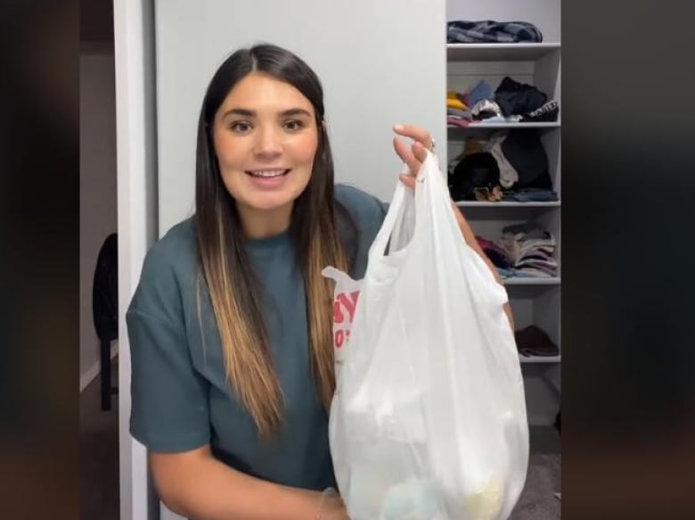 A woman holds up a garbage bag