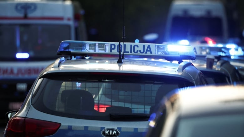 A police car with Polish writing on it is parked with his flashing lights on.