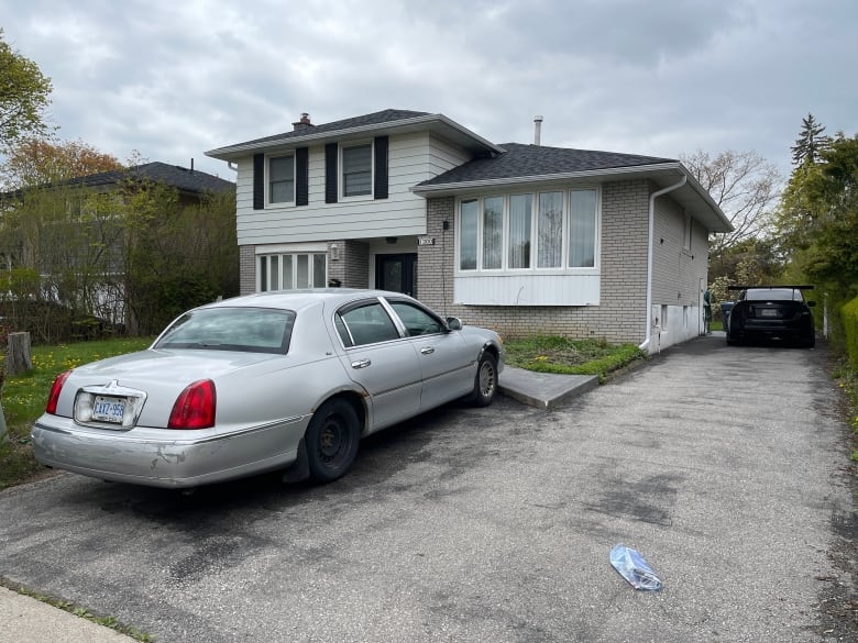 A grey and white house with a silver car parked in the driveway