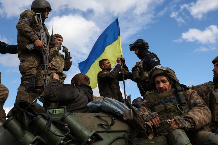 Ukrainian soldiers adjust a national flag near the strategic city of Lyman