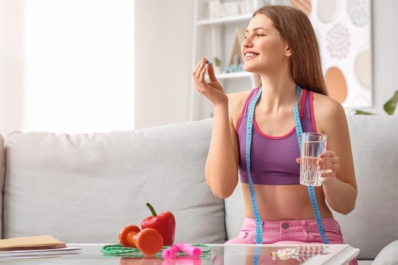 Fit Woman Taking Weight Loss Supplement Pill