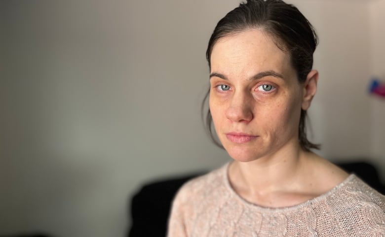 A woman stands in beige-grey room. 