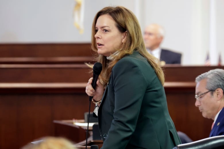 A woman stands at a mic in a legislature