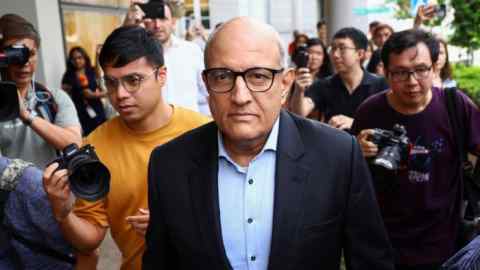 S. Iswaran walking outside the Supreme Court in Singapore surrounded by photographers and media personnel