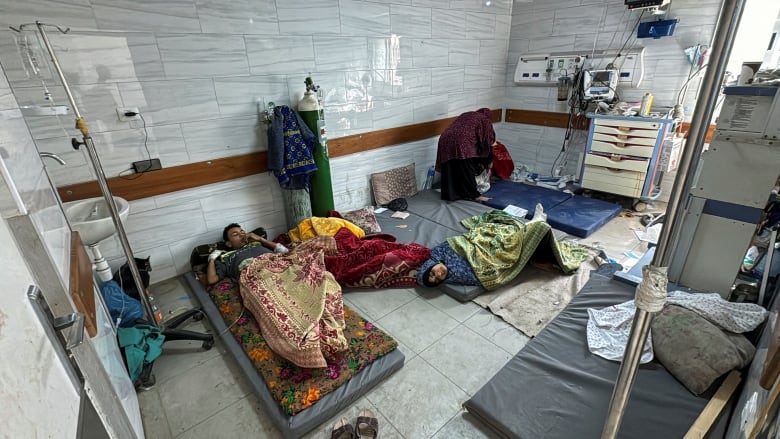 Wounded people lie on mattresses at a hospital.