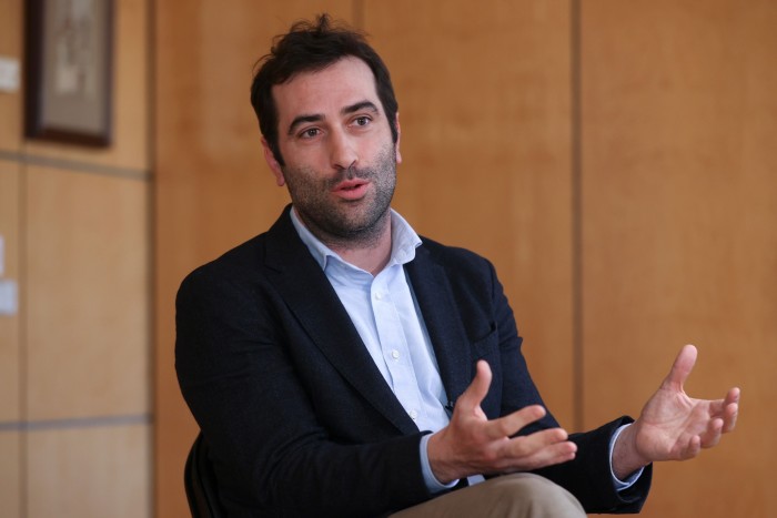 Carlos Cuerpo speaks while seated in an office setting. 