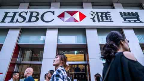 People walking past the signage of an HSBC Holdings Plc bank branch in Hong Kong.