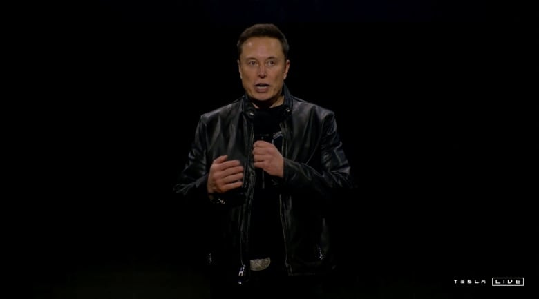 A man in a black leather jacket holds a microphone.