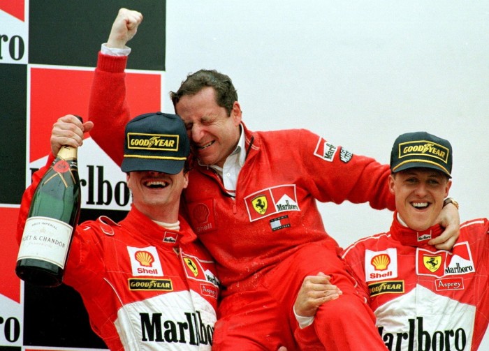 Ferrari F1 drivers Eddie Irvine, left, and Michael Schumacher, right, celebrate their third and first place finish at the 1998 Argentine Grand Prix with team manager Jean Todt