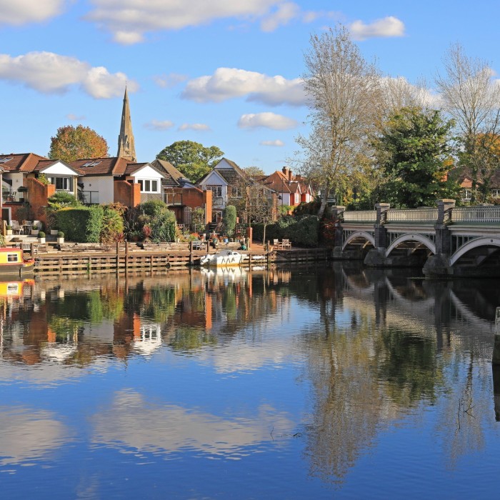 a series of charming riverside houses and lush greenery create a reflection on a calm river