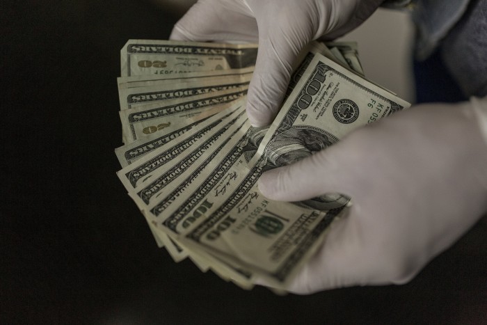 Two hands holding a fan of $100 bills 