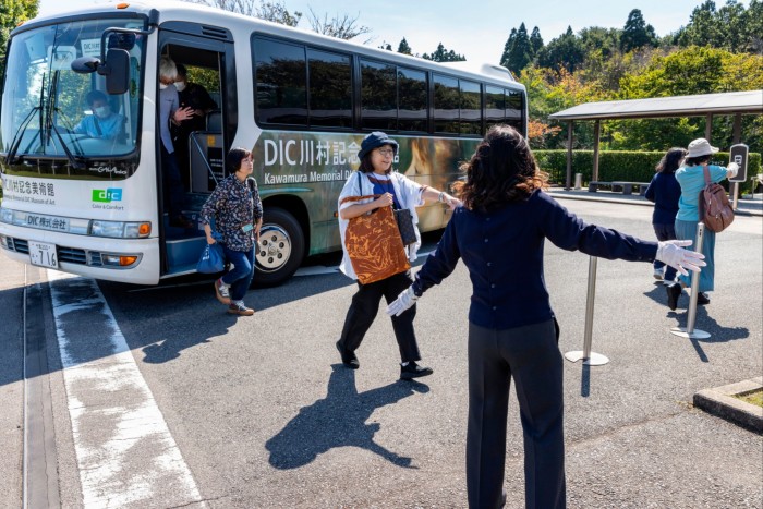 Japanese visitors stepping off a bus marked ‘Kawamura Memorial DIC Museum’