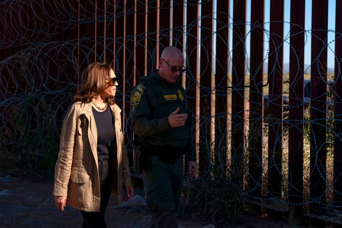 Kamala Harris walks alongside a US Border Patrol official near the US-Mexico border fence topped with barbed wire in Douglas, Arizona