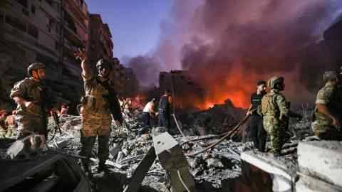 Lebanese army soldiers gather over the rubble of a levelled buildings as people flight the flames, following Israeli air strikes in the Haret Hreik neighbourhood of Beirut’s southern suburbs