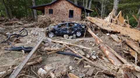 A destroyed car sits amidst debris in front of a destroyed home in Barnardsville, North Carolina