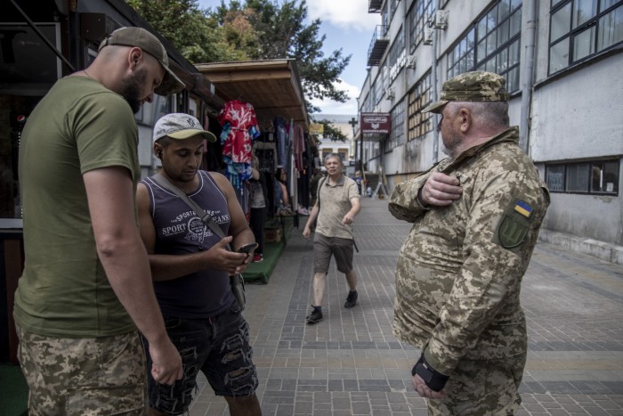 Members of the Kharkiv regional recruitment office check a civilian’s documentation