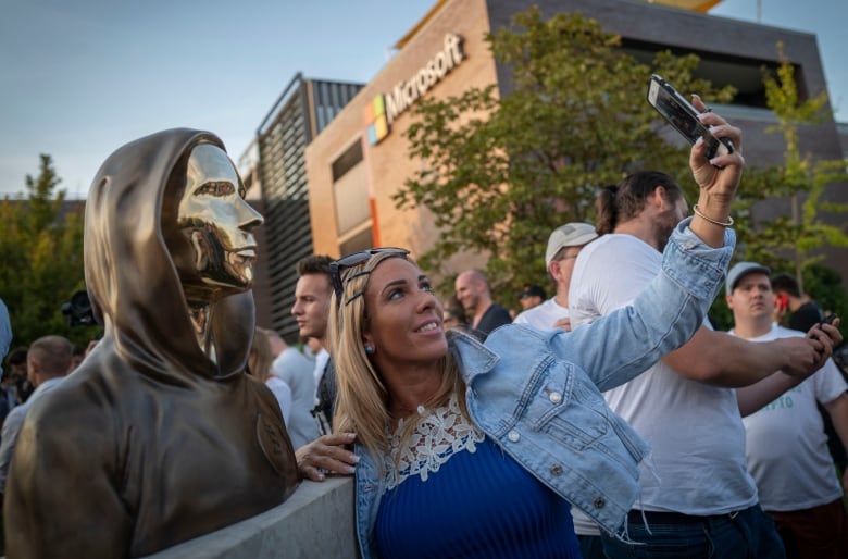 A woman takes a selfie with a statue.