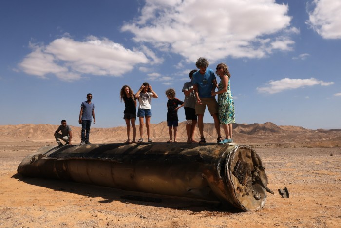 People stand on the remains of a missile