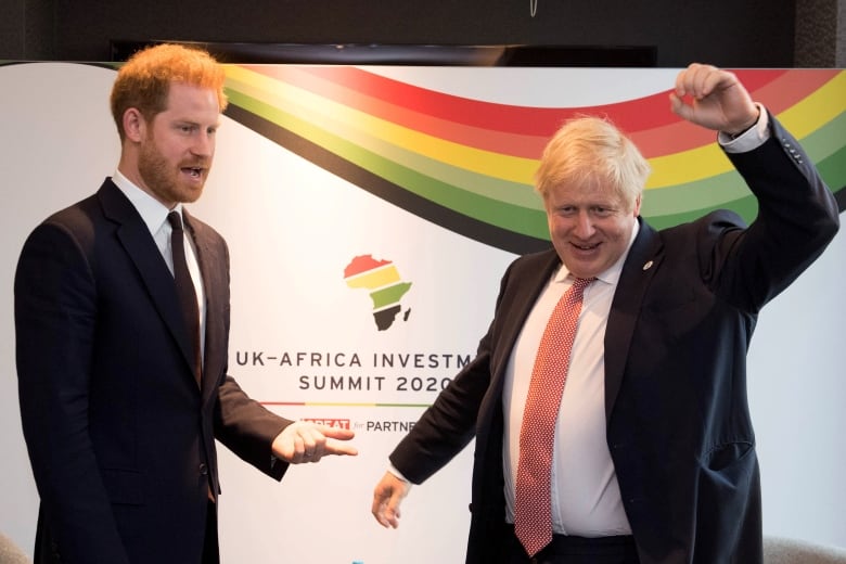 Two people stand in front of a large sign that says 'UK-Africa Investment Summit 2020.'