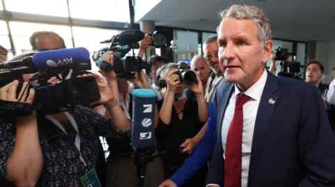 Björn Höcke is seen arriving at Thuringia's state parliament on September 1 2024. He is surrounded by a crowd of journalists and photographers, with several microphones and cameras directed towards him.