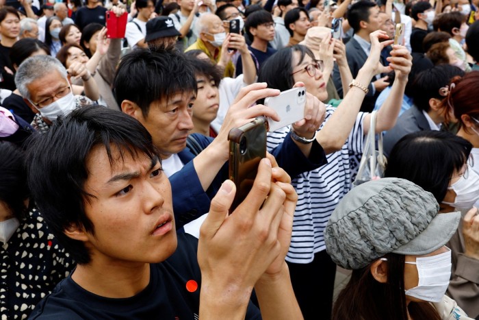 people hold up phones at a campaign rally