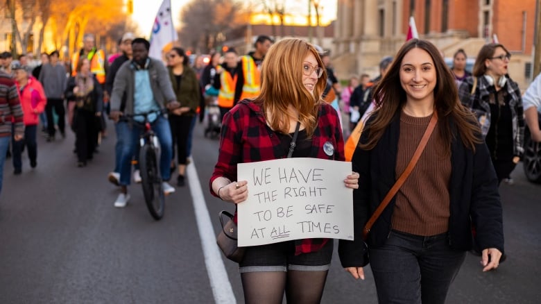 Two people hold a sign that says we have a right to be safe at all times