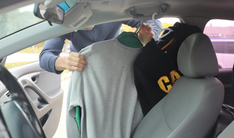 A man sorts through clothes in his car.