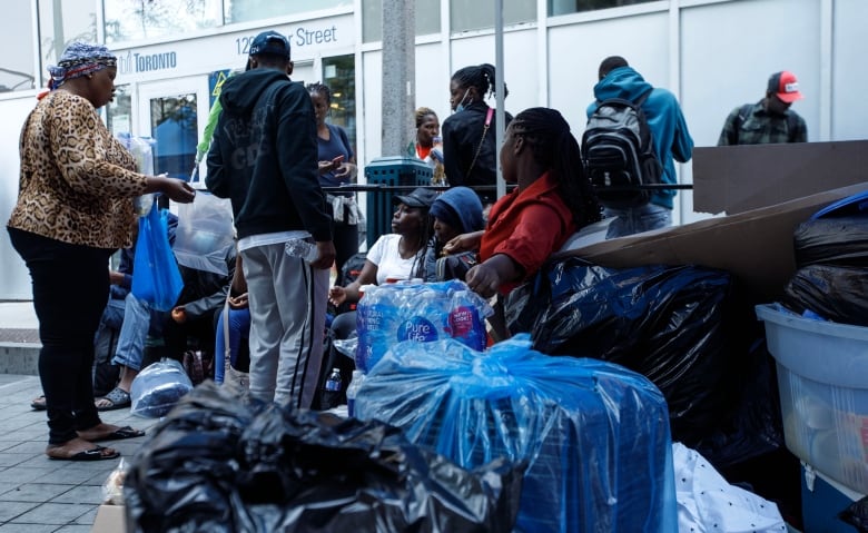 Asylum seekers from Africa and other locales are seen outside of a shelter intake office at Peter St. and Richmond St. in Toronto, on July 14, 2023.