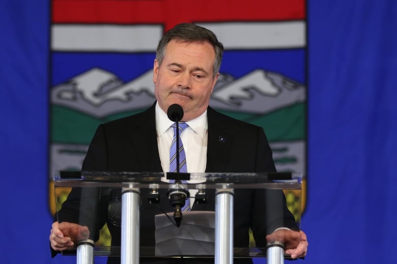 Man frowns while standing before giant Alberta flag