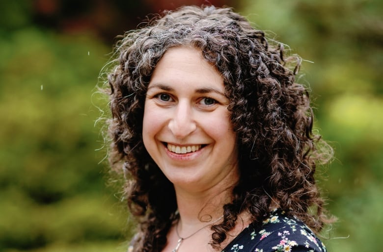 Woman with shoulder-length curly hair smiles at the camera.