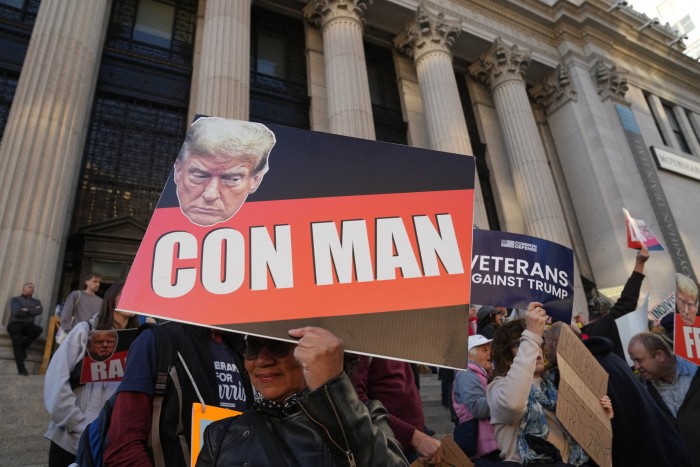 A placard with Donald Trump’s face and the words ‘Con man’ in big capital letters at a street demonstration