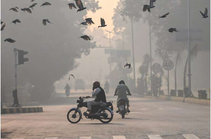 Commuters make their way amid smog in Lahore