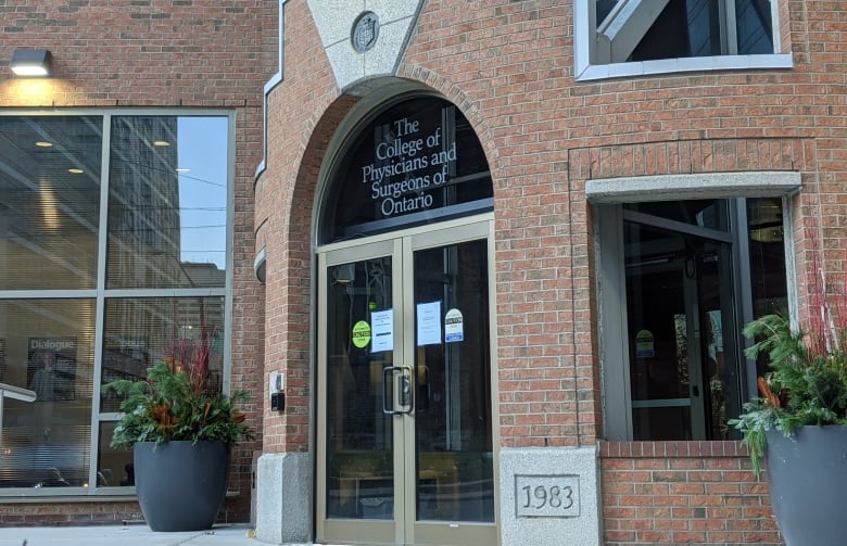 A brick building that says "College of Physicians and Surgeons of Ontario" on a window above a door.