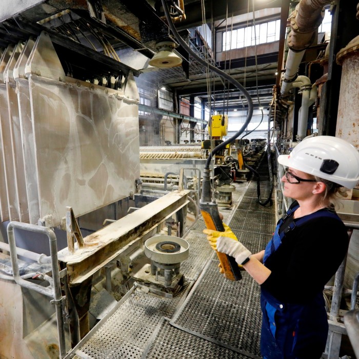 A man in a hard hat observes machines in a factory 